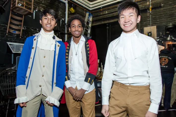 Three students wearing red, white, and blue costumes, backstage