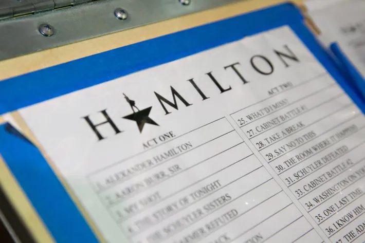 Clipboard with the Hamilton run of show tacked on with blue electrical tape