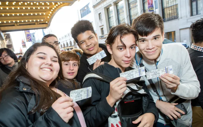 Excited students outside theater in 2017, holding up their tickets