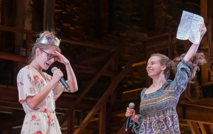 EduHam performers. One wearing a crown looking forlorn, the other looking exuberant waving a copy of the Declaration of Independence