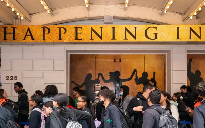 Students lining up to enter the theater. Some are wearing face masks.